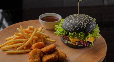 Patates ve sosu bir ahşap zemin üzerine siyah burger