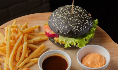 Patates ve sosu bir ahşap zemin üzerine siyah burger