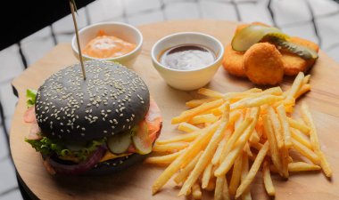 Patates ve sosu bir ahşap zemin üzerine siyah burger