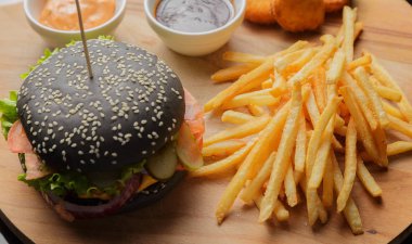 Patates ve sosu bir ahşap zemin üzerine siyah burger