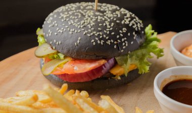 Patates ve sosu bir ahşap zemin üzerine siyah burger