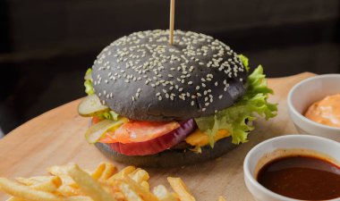 Patates ve sosu bir ahşap zemin üzerine siyah burger