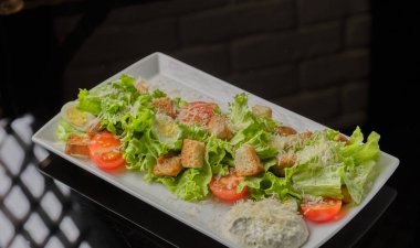 Sezar salatası beyaz bir tabak ve cam arka plan