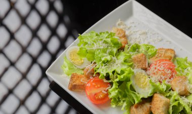 Sezar salatası beyaz bir tabak ve cam arka plan