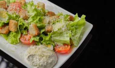 Sezar salatası beyaz bir tabak ve cam arka plan