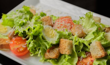 Sezar salatası beyaz bir tabak ve cam arka plan