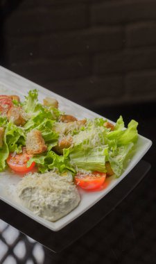 Sezar salatası beyaz bir tabak ve cam arka plan