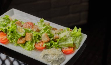 Sezar salatası beyaz bir tabak ve cam arka plan