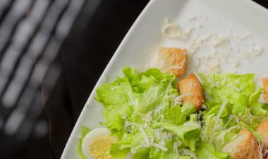 Sezar salatası beyaz bir tabak ve cam arka plan