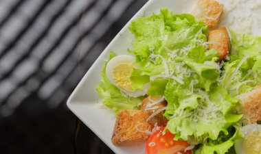 Sezar salatası beyaz bir tabak ve cam arka plan