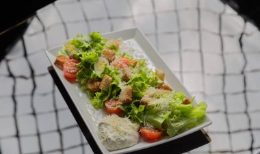 Sezar salatası beyaz bir tabak ve cam arka plan