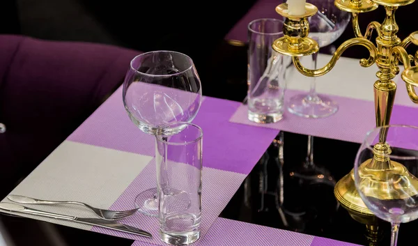 Glasses and a candlestick on a glass table in a restaurant. Romantic setting — Stock Photo, Image