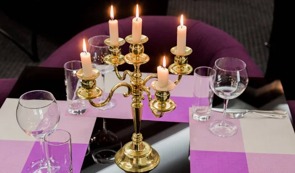 Glasses and a candlestick on a glass table in a restaurant. Romantic setting — Stock Photo, Image