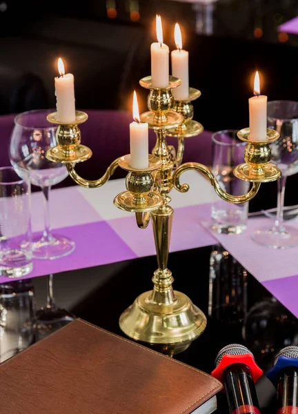 Glasses and a candlestick on a glass table in a restaurant. Romantic setting. Microphones for karaoke — Stock Photo, Image