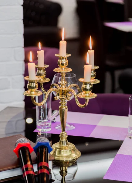 Glasses and a candlestick on a glass table in a restaurant. Romantic setting. Microphones for karaoke — Stock Photo, Image