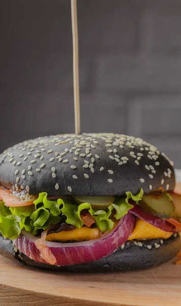 Schwarzer Burger auf Holzgrund mit Kartoffeln und Soße — Stockfoto