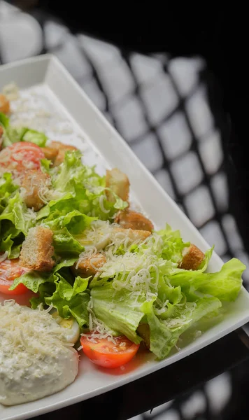 Sezar salatası beyaz bir tabak ve cam arka plan