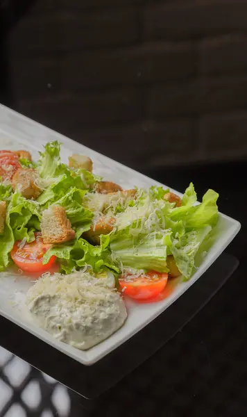 Salada Caesar em uma placa branca e um fundo de vidro — Fotografia de Stock