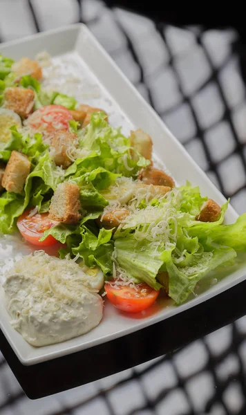 Salada Caesar em uma placa branca e um fundo de vidro — Fotografia de Stock