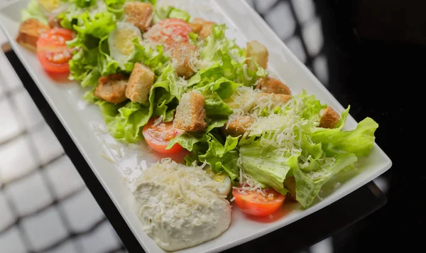 Insalata Cesare su un piatto bianco e uno sfondo di vetro — Foto Stock