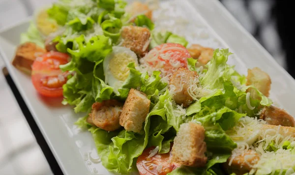 Sezar salatası beyaz bir tabak ve cam arka plan