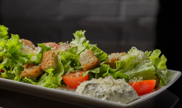 Salada Caesar em uma placa branca e um fundo de vidro — Fotografia de Stock