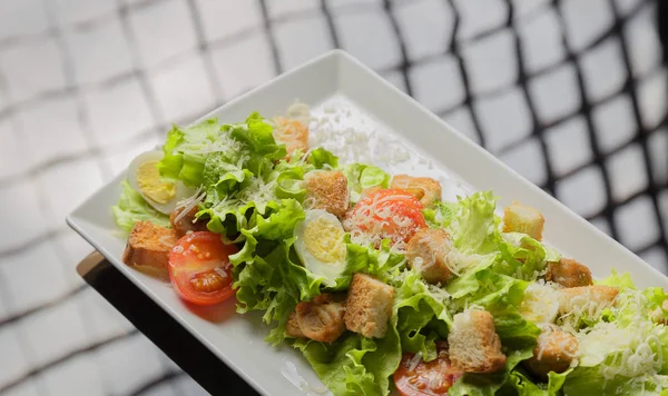 Insalata Cesare su un piatto bianco e uno sfondo di vetro — Foto Stock