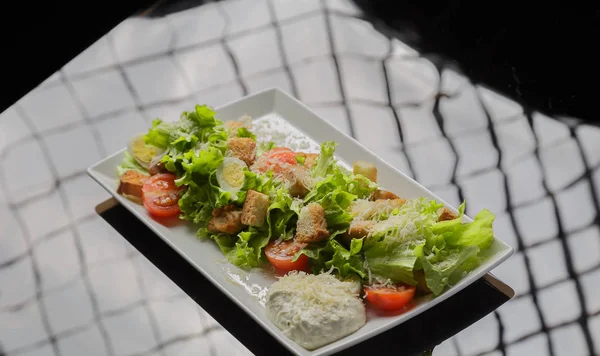 Insalata Cesare su un piatto bianco e uno sfondo di vetro — Foto Stock