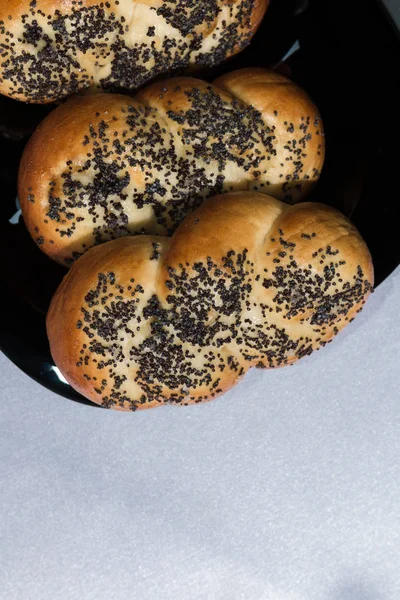 Buns with poppy seeds on a black plate and blue napkin — Stock Photo, Image