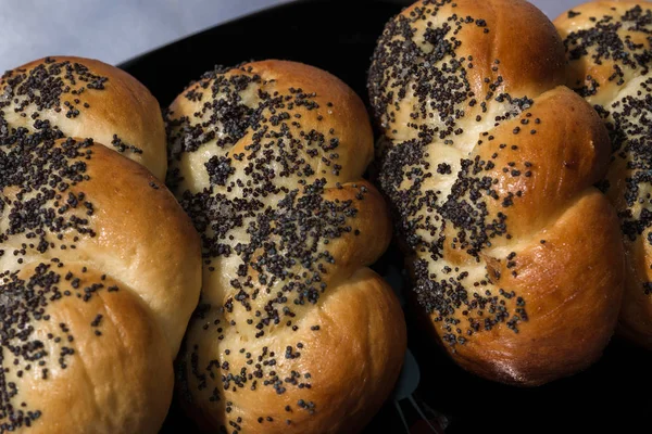 Buns com sementes de papoula em uma placa preta e guardanapo azul — Fotografia de Stock