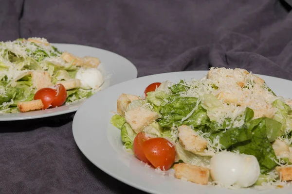 Salada Caesar em um prato branco e um fundo escuro — Fotografia de Stock