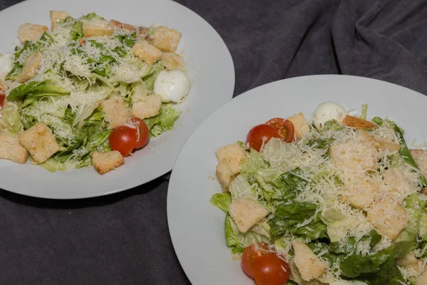 Salada Caesar em um prato branco e um fundo escuro — Fotografia de Stock