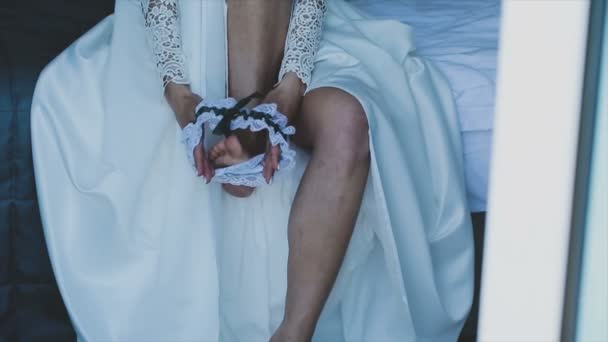 Woman in wedding dress puts on garter on foot — Stock Video