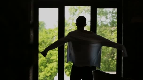 Evde, cam kenarında duran tişörtün üstünde ağır çekim koyarak adam — Stok video