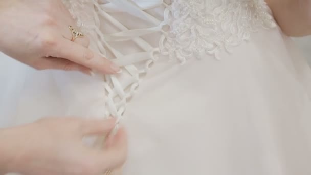 Homme attachant un corset sur la robe de mariée des mariées — Video