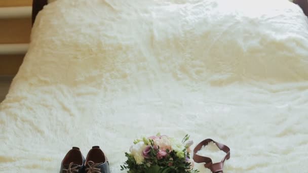 Detalles de la boda. Los novios zapatos de boda, corbata, ramo y anillos en una silla — Vídeos de Stock