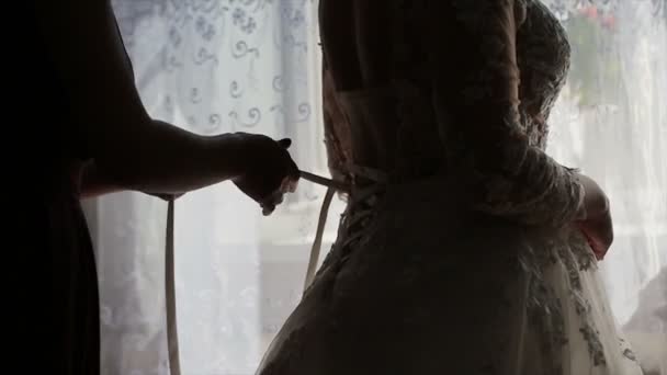 Homme attachant un corset sur la robe de mariée des mariées — Video