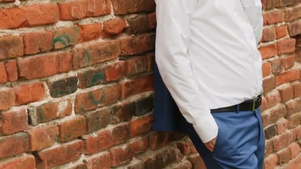 Un homme est debout près d'un mur de briques dans une chemise blanche — Video