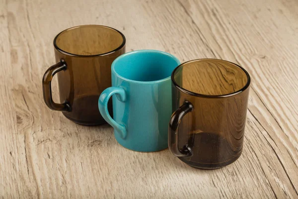 Three cups on a wooden background in different positions. — Stock Photo, Image