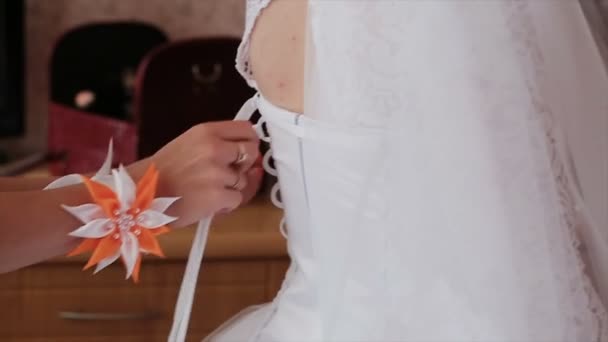 Чоловік зав'язує корсет на весільній сукні наречених — стокове відео
