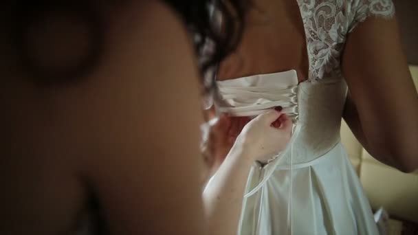 Мужчина привязывает корсет к свадебному платью невесты — стоковое видео