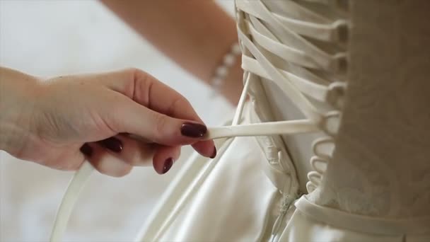 Man tying a corset on the brides wedding dress — Stock Video