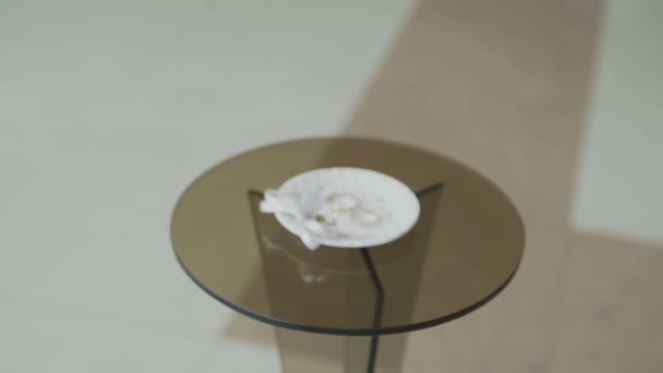 Обручальные кольца на стеклянном столе — стоковое видео