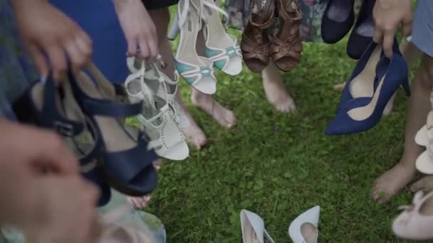 Chicas sosteniendo sandalias en sus manos, sonriendo y bromeando — Vídeos de Stock