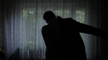 Evde, cam kenarında duran tişörtün üstünde ağır çekim koyarak adam.