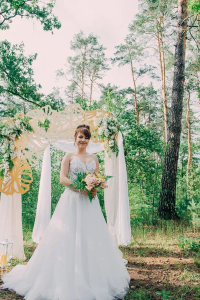 Mulher bonita em um vestido de noiva em uma fotozona decorada com flores frescas, posando e retrato . — Fotografia de Stock