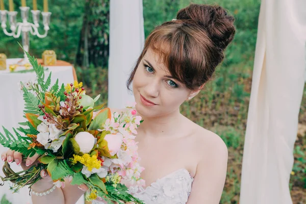 Красива жінка у весільній сукні на фотозоні, прикрашеній свіжими квітами, позуванням та портретом . — стокове фото