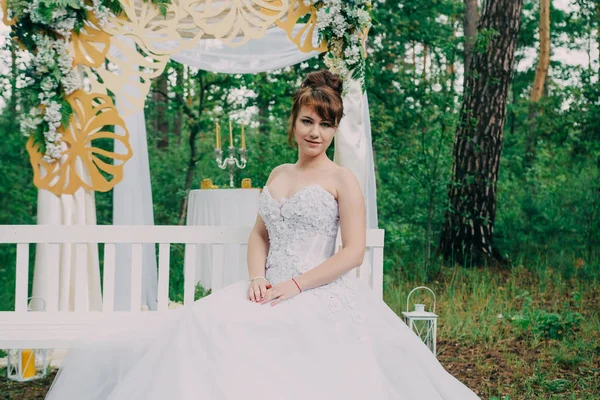 Mulher bonita em um vestido de noiva em uma fotozona decorada com flores frescas, posando e retrato . — Fotografia de Stock