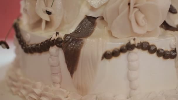 Vértes friss fehér orchidea és a gyöngyök díszített esküvői torta, zöld fű a háttérben — Stock videók