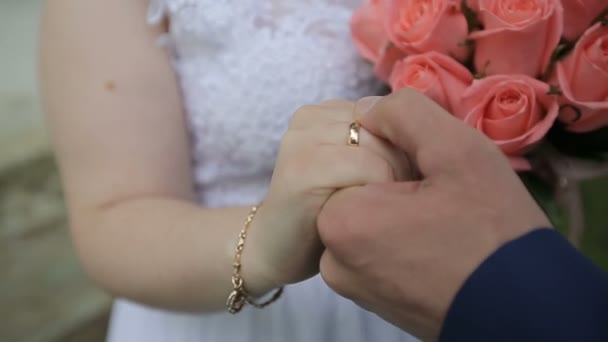 Close-up van bruid en bruidegom bruiloft ringen uitwisselen via groene natuur achtergrond — Stockvideo